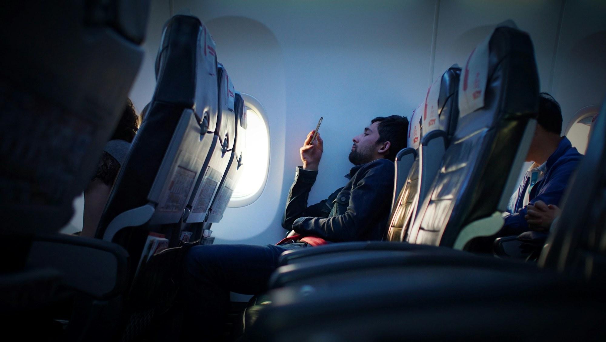 Reiziger gebruikt een smartphone aan boord van een vliegtuig